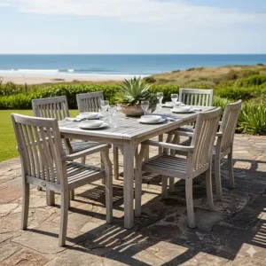 Close-up shot of a durable, weathered teak outdoor dining table and chairs, showcasing the natural aging process ideal for coastal environments.