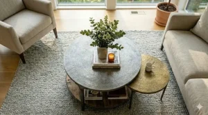 Overhead view of a styled round coffee table with a ceramic vase, candles, and a tray.