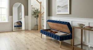 Grey linen tufted storage bench with a hinged lid used for organizing shoes in a hallway.