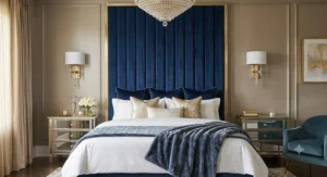 Tall navy blue velvet channel tufted headboard framed by gold wall sconces in a chic glam bedroom