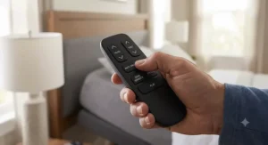 Hand holding a wireless remote control pressing the preset anti-snore button on an adjustable bed base