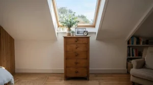 A space-saving tall narrow dresser for closet-free bedrooms fitted beneath a sloped attic ceiling.